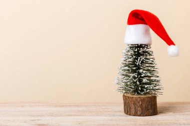 One small Christmas tree with santa hat on colored background. new year decoration with copy space.