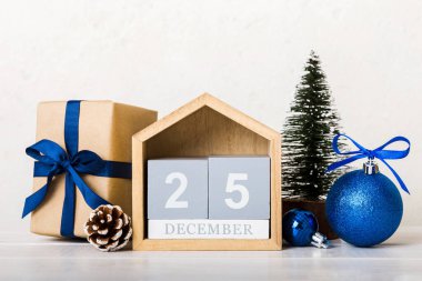 25 december. Christmas composition on colored background with a wooden calendar, with a gift box, toys, bauble copy space.