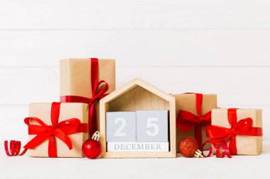 25 december. Christmas composition on colored background with a wooden calendar, with a gift box, toys, bauble copy space.