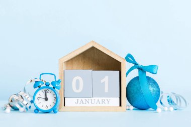 1 january. Christmas composition on colored background with a wooden calendar, with a gift box, toys, bauble copy space.