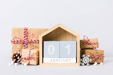 1 january. Christmas composition on colored background with a wooden calendar, with a gift box, toys, bauble copy space.
