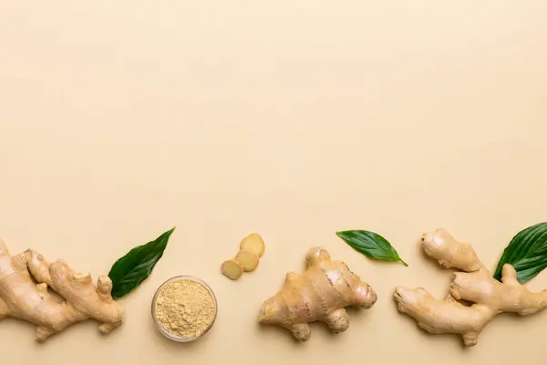 Finely dry Ginger powder in bowl with green leaves isolated on colored background. top view flat lay.