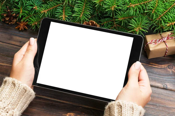 Female hand holding tablet, perspective view. Winter holidays sales background. Christmas online shopping.