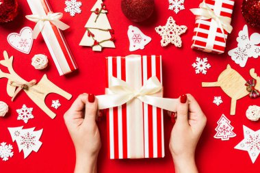 Noel hediyesini kırmızı arka planda tutan kadınların üst görüntüsü. Tatil süslemeleri. Yeni yıl tatili konsepti.
