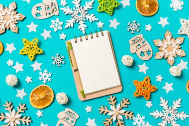 Yeni yıl oyuncakları ve dekorasyonlarıyla mavi arka plandaki defterin en üst görüntüsü. Noel zamanı konsepti.