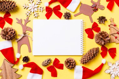 Noel oyuncakları ve dekorasyonlarla dolu sarı bir arka plan. Defterin en üst görüntüsü. Mutlu yıllar konsepti.