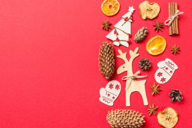 Noel oyuncakları, ren geyikleri ve yılbaşı ağaçlarıyla süslenmiş kırmızı arka plan manzarası. Kopya alanı ile tatil kavramı.