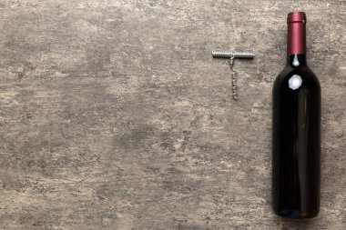 Renkli masada tirbuşonlu bir şişe kırmızı şarap. Düz konum, üst görünüm kopyalama alanı.