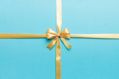 Altın kurdelenin üst görüntüsü yuvarlandı ve sarı fiyonk renkli arka planda izole edildi. Kopyalama alanı olan düz.