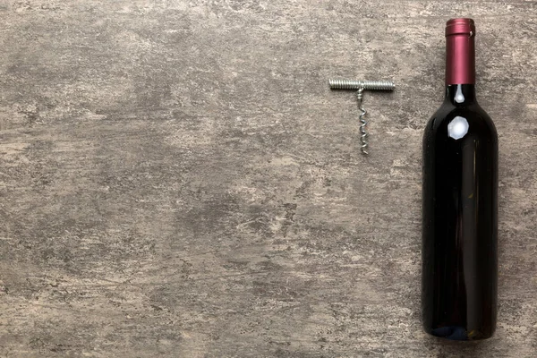 Renkli masada tirbuşonlu bir şişe kırmızı şarap. Düz konum, üst görünüm kopyalama alanı.