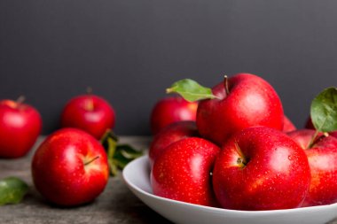 Masanın üstündeki tabakta ya da kasede kırmızı elmalar var. Boşluğu kopyala.