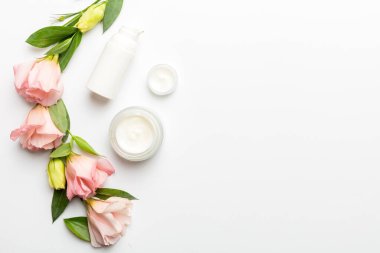 Kozmetik ürünleri ve beyaz arka planda güzel güller olan kompozisyon. Uzayı kopyala, düz yat.