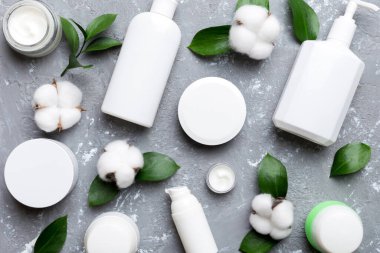 Pamuk çiçekli organik kozmetik ürünler ve çimento arka planında yeşil yapraklar. Düz yatıyordu.