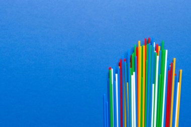 Renkli arka planda renkli plastik pipetler, düz yatış. Metin için Boşluğu Kopyala.