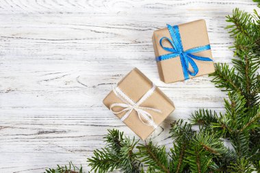 Çam kozalakları ve çam dalları ile karanlık rustik ahşap masa üzerinde Noel hediyeleri sarılmış. Metniniz için kopya alanı ile.