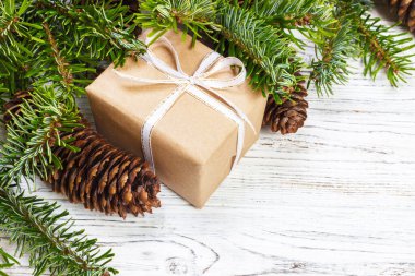 Noel hediye kutusu beyaz ahşap masa arka plan, Ladin şube, çam kozalakları, çerçeve, üstten görünüm, metin için yer.