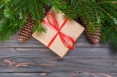 Noel ağacı dalı, süslemeleri ve hediye kutusu beyaz ahşap masa üzerinde.