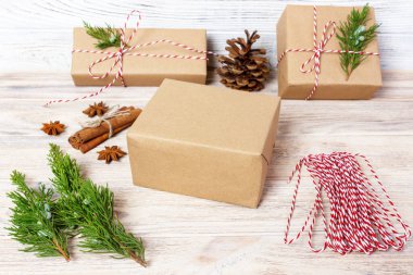 Yaratıcı hobi. Hediye. Saten kurdele ile şık gri kağıt modern Noel hediyesi ambalaj kutuları. Üstten Görünüm ahşap masa köknar ağacı dalları, dekorasyon ile.