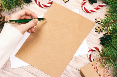 Ünlü bir el, tahta arka planda bir Noel mektubu yazıyor. Ayarlanmış.