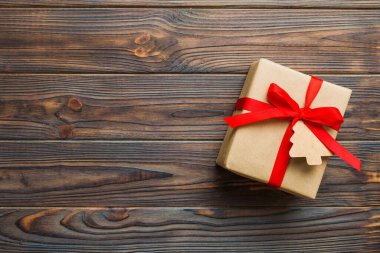 wrapped christmas or other holiday handmade present in paper with colored ribbon. Present box, decoration of gift on colourfull table, top view with copy space.