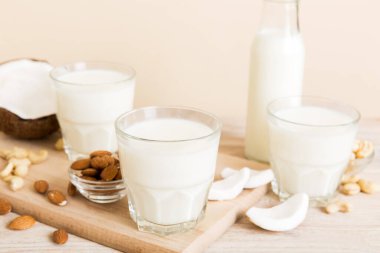 Masa arkasında çeşitli vejetaryen süt bademi, hindistan cevizi, fındık. Vejetaryen bitkisi sütü ve malzemeleri, üst görünüm.