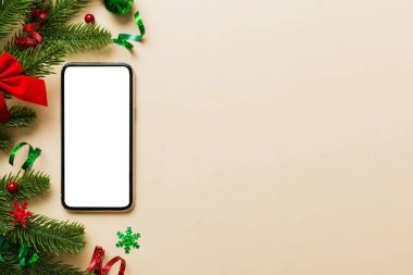 Mesaj atmak için yeri olan bir Noel modeli. Noel reklamı, uygulama şablonu. Masa arkasında boş ekran olan el ele tutuşan telefon. Mutlu yıllar ve Xmas Flat.