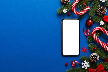 Mesaj atmak için yeri olan bir Noel modeli. Noel reklamı, uygulama şablonu. Masa arkasında boş ekran olan el ele tutuşan telefon. Mutlu yıllar ve Xmas Flat.
