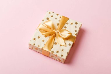 Noel 'i ya da diğer tatil hediyelerini renkli arka planda altın kurdeleli beyaz kağıda sardım. Şimdiki kutu, renkli tabloda hediye süslemesi, kopya alanı ile üst görünüm.