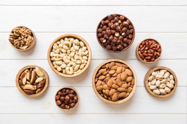 mixed nuts in wooden bowl. Mix of various nuts on colored background. pistachios, cashews, walnuts, hazelnuts, peanuts and brazil nuts.