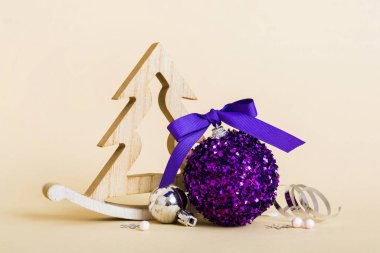 Christmas ball with decorative wooden tree on colored background. decoration bauble with ribbon bow with copy space.