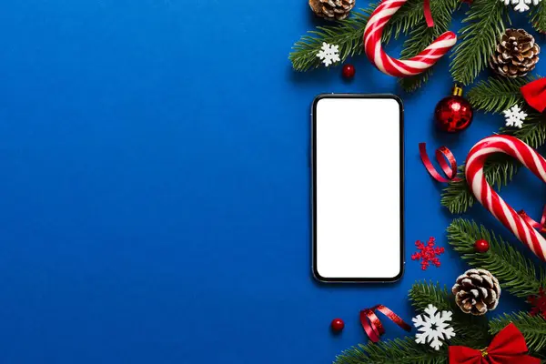 Mesaj atmak için yeri olan bir Noel modeli. Noel reklamı, uygulama şablonu. Masa arkasında boş ekran olan el ele tutuşan telefon. Mutlu yıllar ve Xmas Flat.