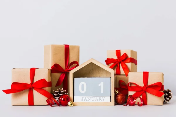 1 january. Christmas composition on colored background with a wooden calendar, with a gift box, toys, bauble copy space.
