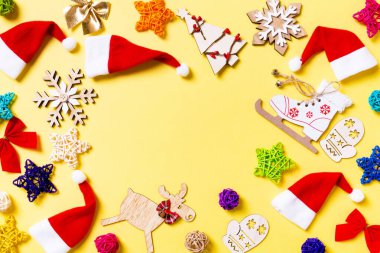 Sarı arka planda Noel süsleri ve Noel Baba şapkaları. Fotokopi alanı ile iyi tatiller.