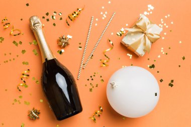 Renkli arka planda şampanya şişesi hediye paketi kurdeleleri ve konfetilerin düz kompozisyonu vardı. Düz konum, üst görünüm tatil konsepti.