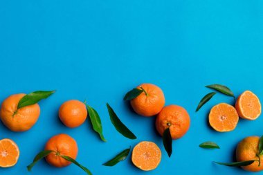 Renkli arkaplanda yeşil yaprakları, üst görünümü, metin için alanı olan bir sürü olgun mandalina..