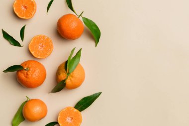 Renkli arkaplanda yeşil yaprakları, üst görünümü, metin için alanı olan bir sürü olgun mandalina..