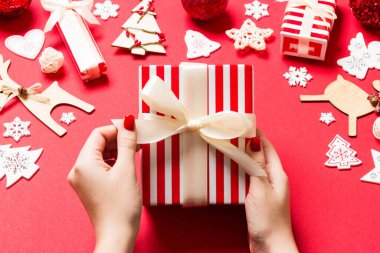Noel hediyesini kırmızı arka planda tutan kadınların üst görüntüsü. Tatil süslemeleri. Yeni yıl tatili konsepti.