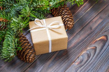 Ahşap arkaplan görünümünde köknar dalları olan hediye kutuları.