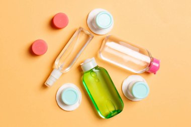 Renkli arka planda kozmetik ürünleri için küçük gezici şişelerin ve kavanozların üst görünümü. Tasarımınız için kopya alanı olan yüz bakımı konsepti.