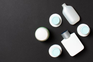 Yüz bakımı için en iyi bakış açısı: şişeler ve kavanozlar dolusu tonik, su, krem, renkli arka planda pamuk pedleri. Fikirleriniz için boş midye içeren vücut bakım konsepti.