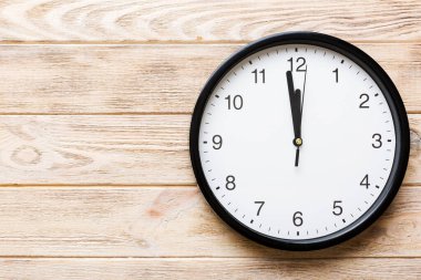 New year celebration concept with a bottle of champagne and two glasses toasting. Christmas gift box, alarm clock and fir tree branch on colored table. Top view Copy space.