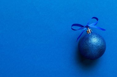 Christmas ball on colored background. decoration bauble with ribbon bow with copy space.
