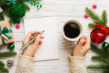 Noel 'i yazmak için bir kadın not defterine Xmas dekorasyonlu renkli arkaplan çiziyor.