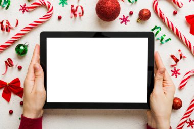 Evden Noel alışverişi, kadın elleri boş beyaz ekranlı tableti tutuyor. Kadın elinde tablet, boş ekran, Noel ağacı ve arka planda hediyeler..