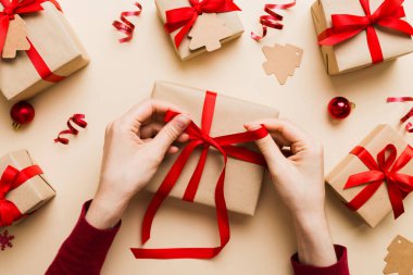 Kadınlar Noel tatili için sürpriz hediyeler hazırlıyor. İş yerinde el aletleri ve manzarayla oturuyor. Renkli masada Noel hediyesini paketleyen kadın..