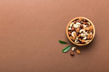 Renkli masadaki ahşap kasede fındık çeşitleri. Ceviz, fındık, ceviz, badem. Fındık Üst görünümü ile kopyalama alanını karıştır.