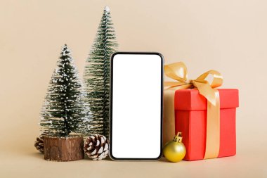 Digital phone mock up with rustic Christmas decorations for app presentation with empty space for you design. Christmas online shopping concept. Tablet with copy space on colored background.