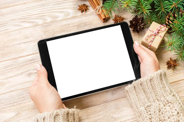 Female hand holding tablet, perspective view. Winter holidays sales background. Christmas online shopping.