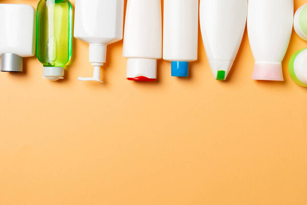 Top view of cosmetic products in different jars and bottles on colored background. Close-up of containers with copy space.