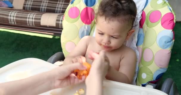Niño Pequeño Sienta Una Silla Alimentación Para Bebés Come Melocotón — Vídeo de stock